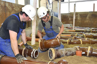 two men installing sewer pipes in testing facility