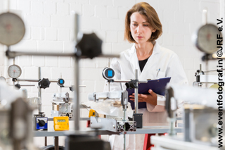 Woman in white smock with clipboard in a test laboratory