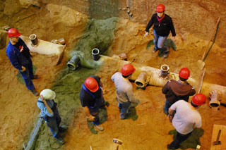 persons with red helmets on the ground of a test facility inspecting lateral connections on a sewer